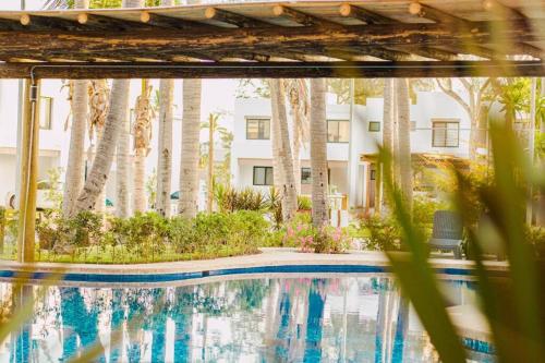 a swimming pool in front of a building with trees at Familiar Departamento Cerca de la Playa in Mazatlán