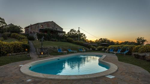 a swimming pool in a yard with chairs and a house at PODERE SAN ANSANO 14&2, Emma Villas in Paganico