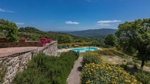 a garden with a pool and mountains in the background at PODERE SAN ANSANO 14&2, Emma Villas in Paganico