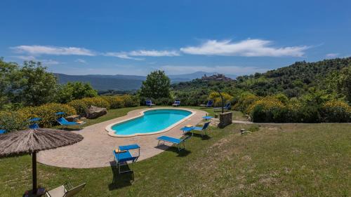 a swimming pool with chairs and an umbrella at PODERE SAN ANSANO 14&2, Emma Villas in Paganico