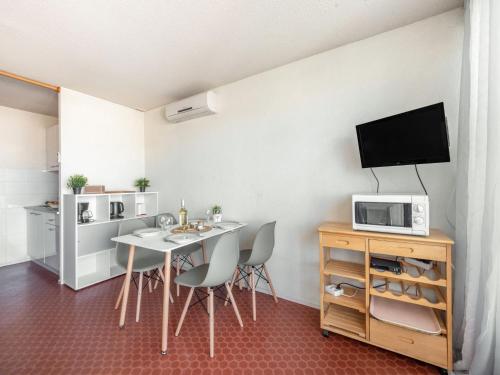 - une salle à manger avec une table, des chaises et un four micro-ondes dans l'établissement Studio Port Nautile-5 by Interhome, au Grau-du-Roi