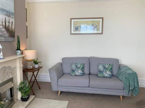 a gray couch in a living room with a fireplace at Bougainvillea in Ventnor