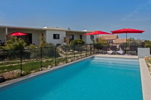 una piscina con sombrillas rojas y una casa en Tramontana quiet place 7 min from beach swimming pool bbq en Calenzana