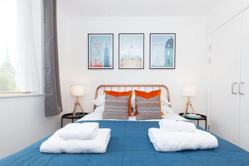 um quarto com uma cama azul com almofadas laranja em Oxfordshire Living - The Tolkien Apartment - Oxford em Oxford