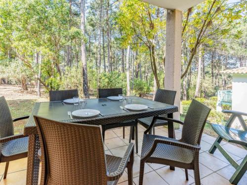 une table et des chaises sur un patio arboré dans l'établissement Apartment Domaine Golf Resort by Interhome, à Lacanau-Océan