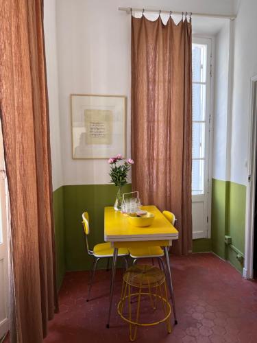 une salle à manger avec une table et des chaises jaunes dans l'établissement L'appartement du Café de l'horloge, à La Ciotat