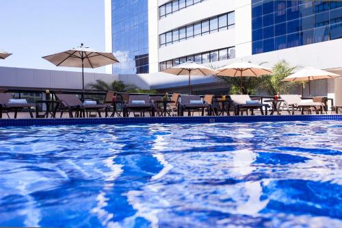 a swimming pool with tables and chairs and umbrellas at Quality Hotel & Suítes São Salvador in Salvador