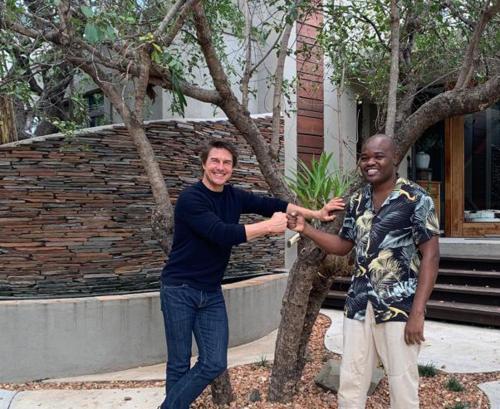 Dois homens estão a apertar as mãos ao lado de uma árvore. em Safari Moon Luxury Bush Lodge em Hoedspruit