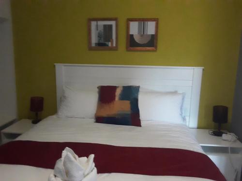 ein Schlafzimmer mit einem weißen Bett mit zwei Bildern an der Wand in der Unterkunft Ramatie Guest Palace in Kasane