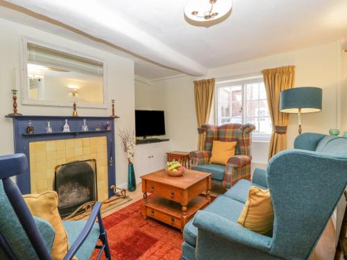 a living room with blue chairs and a fireplace at Bell Cottage in Dorchester