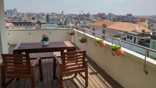 einen Balkon mit einem Holztisch und 2 Stühlen in der Unterkunft Unique Penthouse Porto near Livaria Lello - 40m2 Terrace and Free Parking in Porto