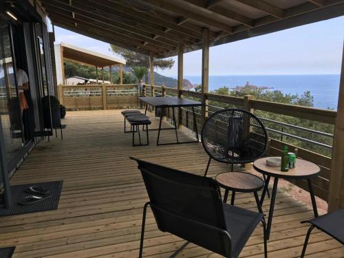 una terrazza in legno con tavoli, sedie e vista sull'oceano di Mobil Home Vue sur Mer - Racine 03 a Saint-Raphaël