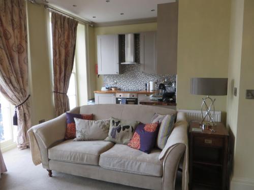 a living room with a couch and a kitchen at Hewlett Apartments in Cheltenham