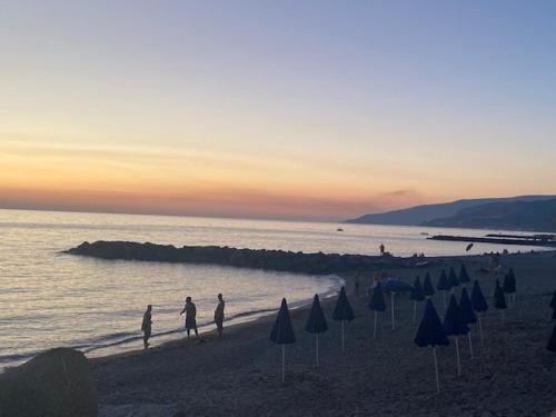 a group of people walking on a beach with umbrellas at Sea Palace Hotel in Marina di Fuscaldo