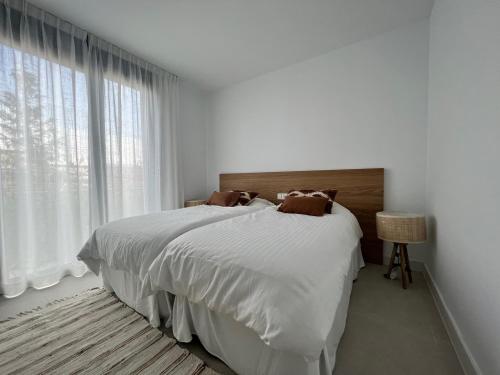 a white bedroom with a large bed and a window at Mesas Homes luxury 4 bed apartment near the sea and port Estepona in Estepona