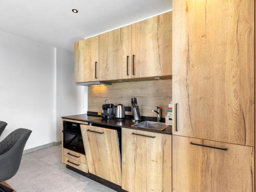 a kitchen with wooden cabinets and a sink at Apartment Emma Deluxe Aparthotel-9 by Interhome in Fürth