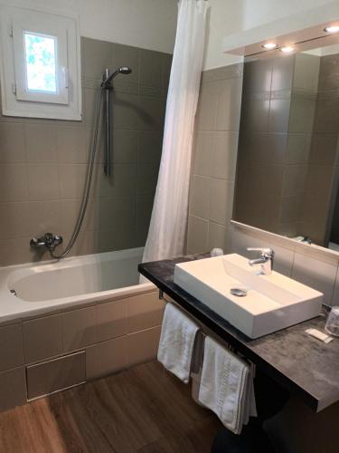 a bathroom with a sink and a tub and a shower at Hotel de La Paix in Corte