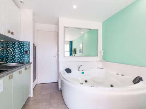 une baignoire blanche dans une salle de bain avec un miroir dans l'établissement Studio L'Esquinade P1 101 by Interhome, à Agay
