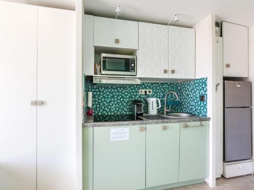 une cuisine avec des armoires blanches et un micro-ondes dans l'établissement Studio L'Esquinade P1 101 by Interhome, à Agay