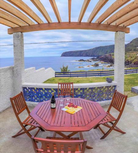 a picnic table with two chairs and a bottle of wine at Casa Beira Mar in Mosteiros