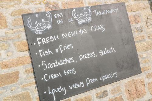 a sign on a brick wall with drawings on it at Driftwood in Marazion