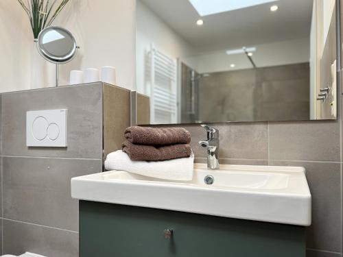 a bathroom with a sink with towels and a mirror at M5 Bungalow - Apartmenthaus Marienburger Str 4 - FERIENDOMIZIL HOLLICH in Grömitz