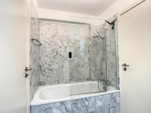 een badkuip in een badkamer met een stenen muur bij Appartement 'Plaza' te Oostduinkerke - Bad in Oostduinkerke-Bad