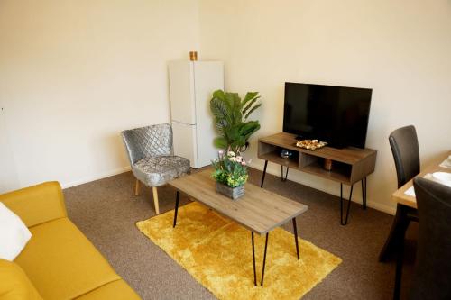 a living room with a couch and a table and a tv at 10BH Dreams Unlimited- Budget Heathrow Long stay Apartment with FREE PARKING in Ashford