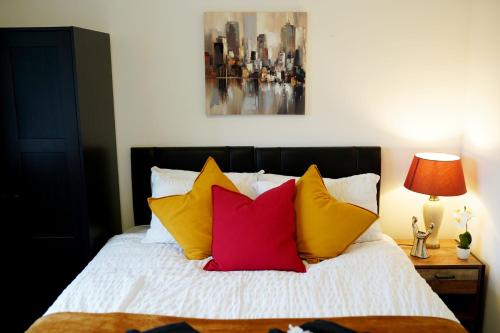 een slaapkamer met een bed met gele en rode kussens bij 10BH Dreams Unlimited- Budget Heathrow Long stay Apartment with FREE PARKING in Ashford