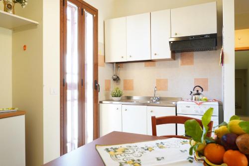 a kitchen with white cabinets and a table with a bowl of fruit at vacanza Taormina mare in Mazzeo