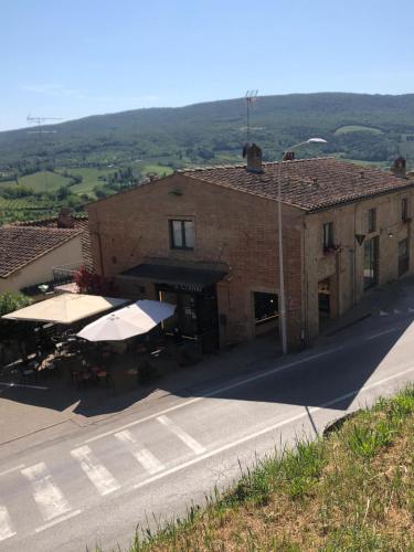 a building with tables and umbrellas on a street at Appartamenti Il Criollo in San Gimignano
