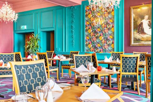 a restaurant with blue walls and tables and chairs at The Grand Hotel in Torquay