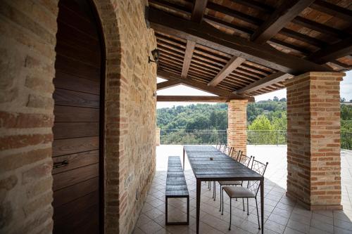 an outdoor patio with a wooden table and chairs at Villa Ermelinda - Matrimoni, piscina e jacuzzi in Castelraimondo