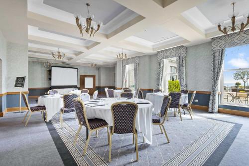 a conference room with tables and chairs and a screen at The Grand Hotel in Torquay