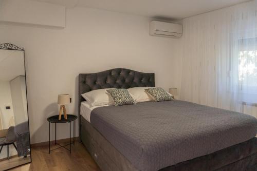 a bedroom with a large bed with a gray headboard at Apartman Sorelle in Kali