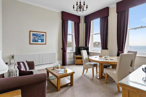 a living room with a table and a dining room at The Grand Hotel in Torquay