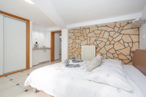 een slaapkamer met een wit bed en een stenen muur bij Apartment Tina in Vrh