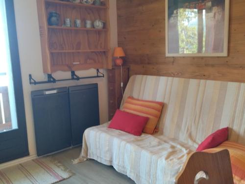 une petite chambre avec un lit avec des oreillers roses et oranges dans l'établissement 2 pièces cabine au pied des pistes avec balcon, cuisine équipée et services optionnels - FR-1-557-64, à Les Adrets