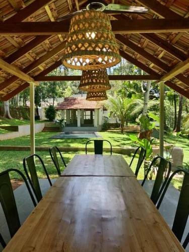una mesa de madera con sillas y una lámpara de araña en Pool Villa - The Humming Trees, Pala, en Lālam