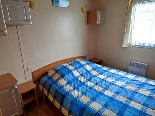 - une chambre avec un lit bleu et blanc et une fenêtre dans l'établissement Le Flamboyant - Piscines chauffees, à Brem-sur-Mer