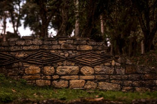 a stone wall in the grass with trees in the background at Hotel Fundo Achamaqui in Chachapoyas
