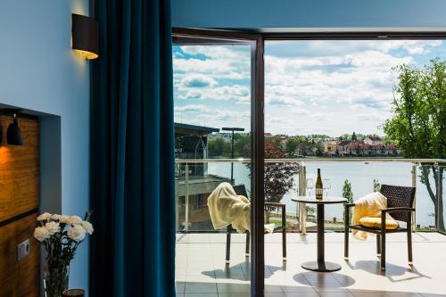 a room with a balcony with a view of the water at Willa Port Apartament Premium z widokiem na jezioro in Ostróda