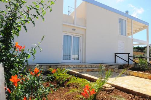 a white house with flowers in front of it at Case Vacanza Viola di Mare in Custonaci