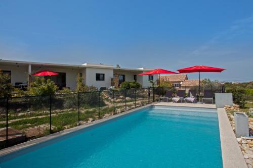 una piscina con sombrillas rojas y una casa en apart Levante shared swimming pool bbq, en Calenzana