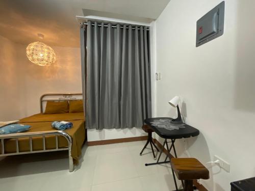 a bedroom with a bed and a desk and a window at Sto. Niño Residences Standard Room in Lucena
