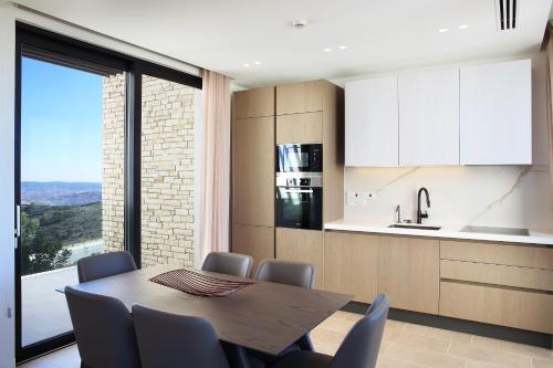 a dining room with a table and chairs and a kitchen at Minthis Resort in Paphos City