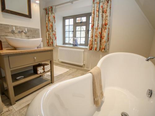 a bathroom with a white tub and a sink at Oma's Cottage in Moreton in Marsh