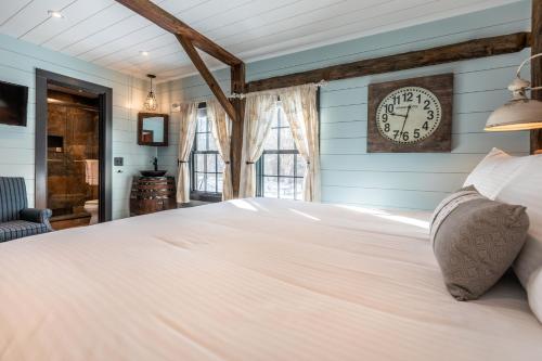 a bedroom with a large white bed with a clock on the wall at The Barnstead Inn in Manchester Center