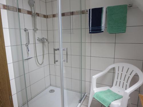 eine Dusche mit einer Glastür und einem Stuhl im Bad in der Unterkunft Natururlaub Frankenau in Frankenau
