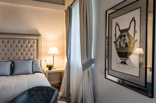a bedroom with a bed and a picture of a vase on the wall at CORTE SAGGIN Charme Relais in San Pietro in Cariano